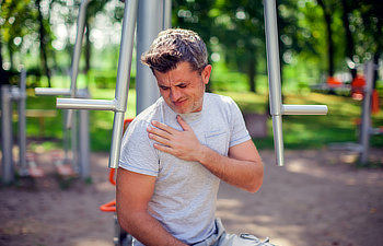 unhappy man feeling pain in his chest during sport and workout in the park