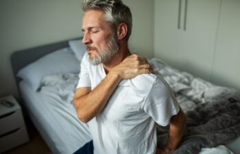 Middle-aged man with shoulder pain in bedroom